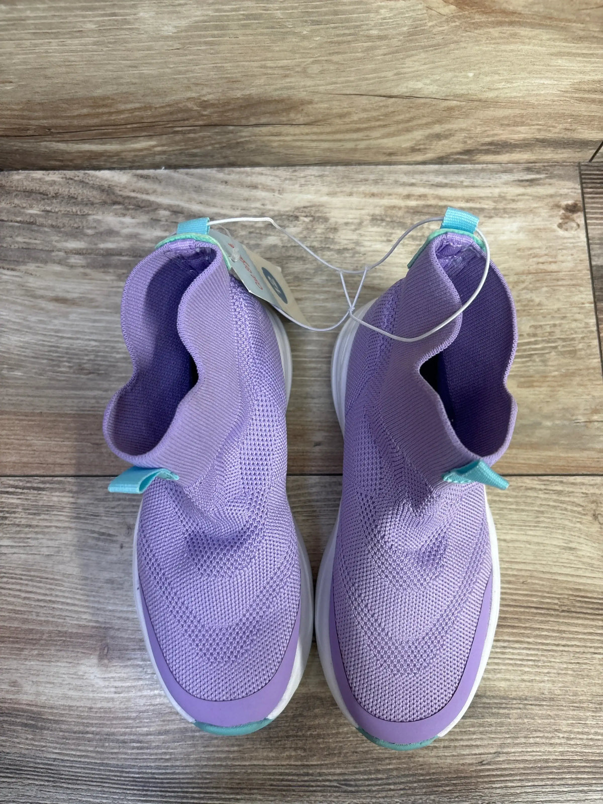 Top down view of Cat and Jack Ari toddler purple slip on knit sneakers showcasing sock like ankle collar and white sole on wood floor