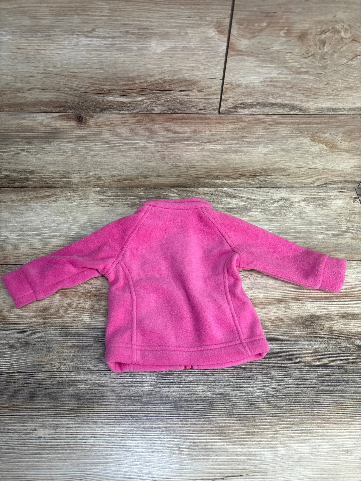 Pink fleece toddler jacket on wood floor, long sleeves, soft outerwear