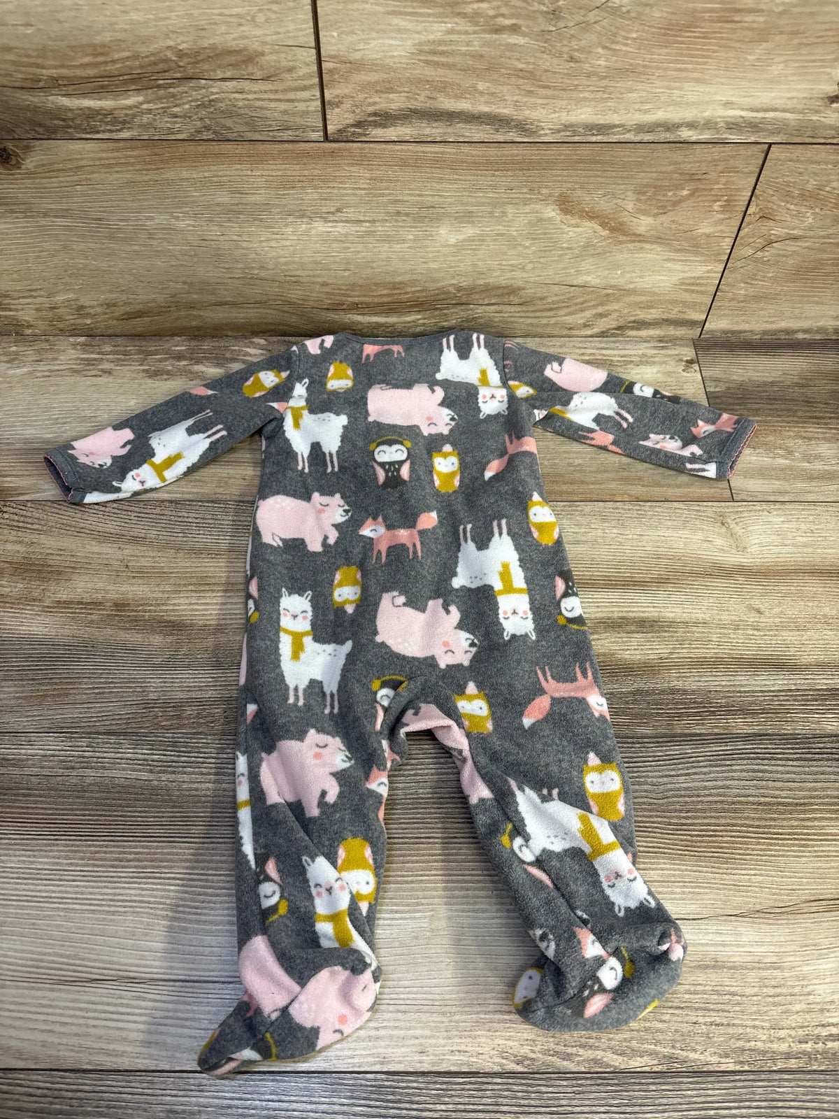 Front view of Simple Joys blanket sleeper showcasing long sleeves, footed legs, and animal print on a wood floor