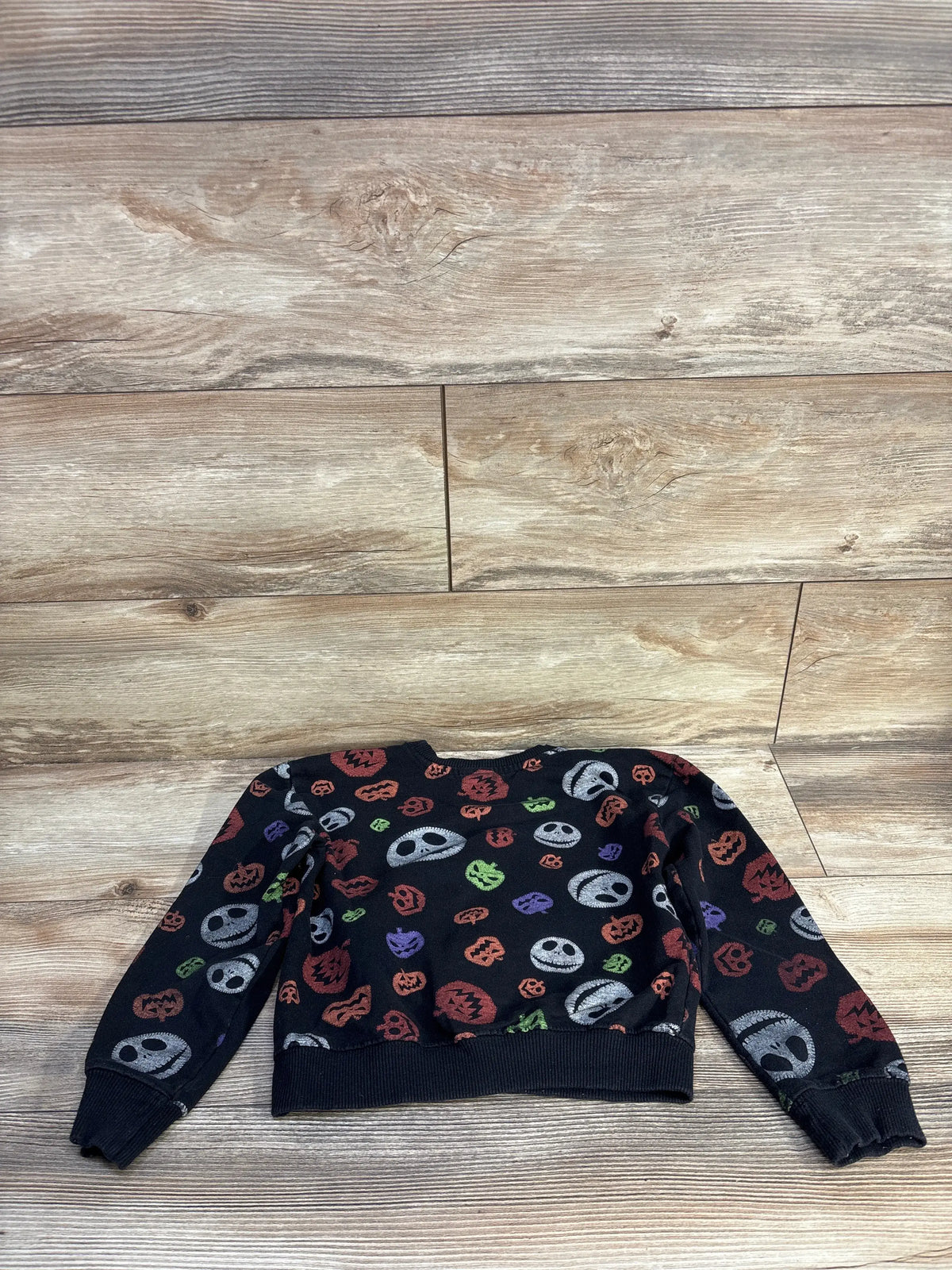 Front view of Disney Nightmare Before Christmas sweatshirt, black size 5T, with colorful graphics on wood-look background