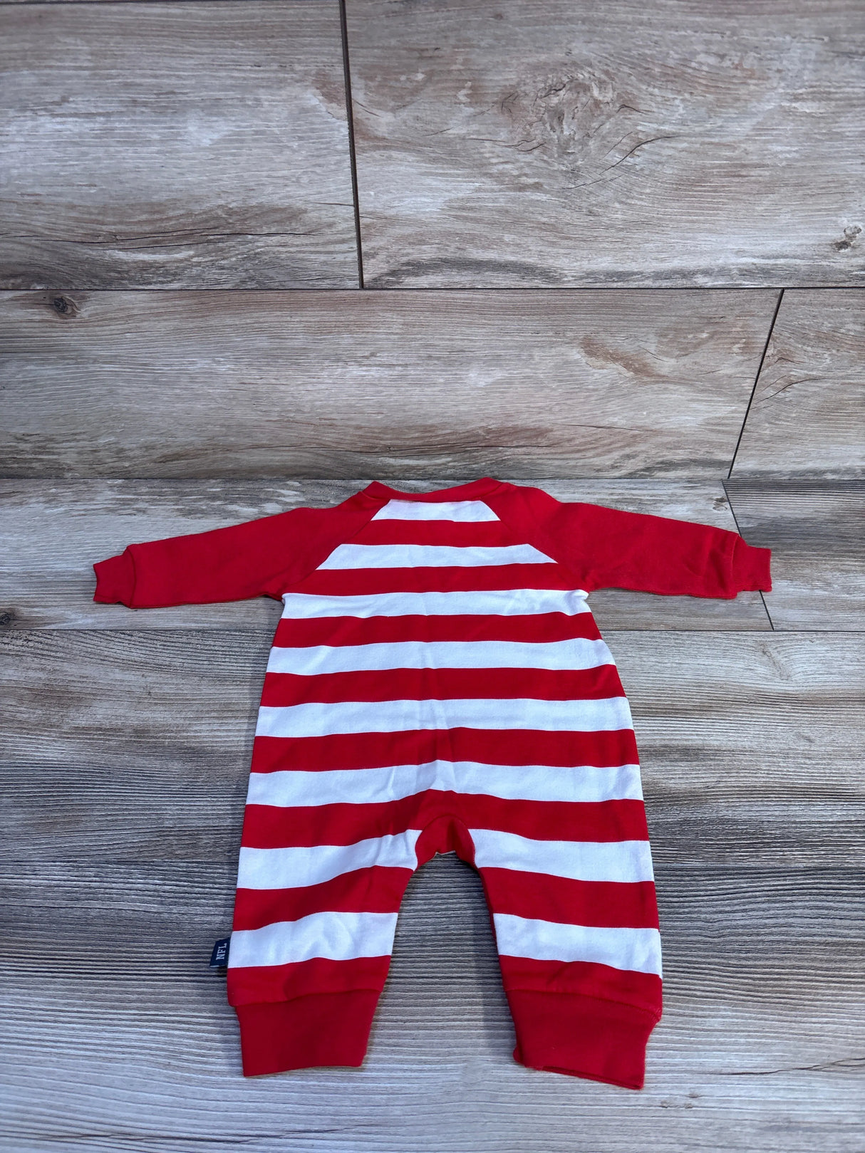 Back flat-lay of newborn Gerber Kansas City Chiefs footless coverall with red and white stripes and red sleeves on wood background