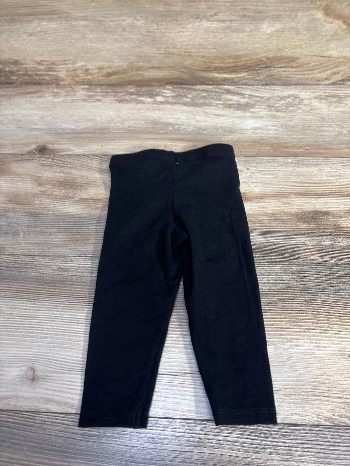 Flat lay of Cat and Jack black toddler leggings showing elastic waistband and ankle-length fit on wood background