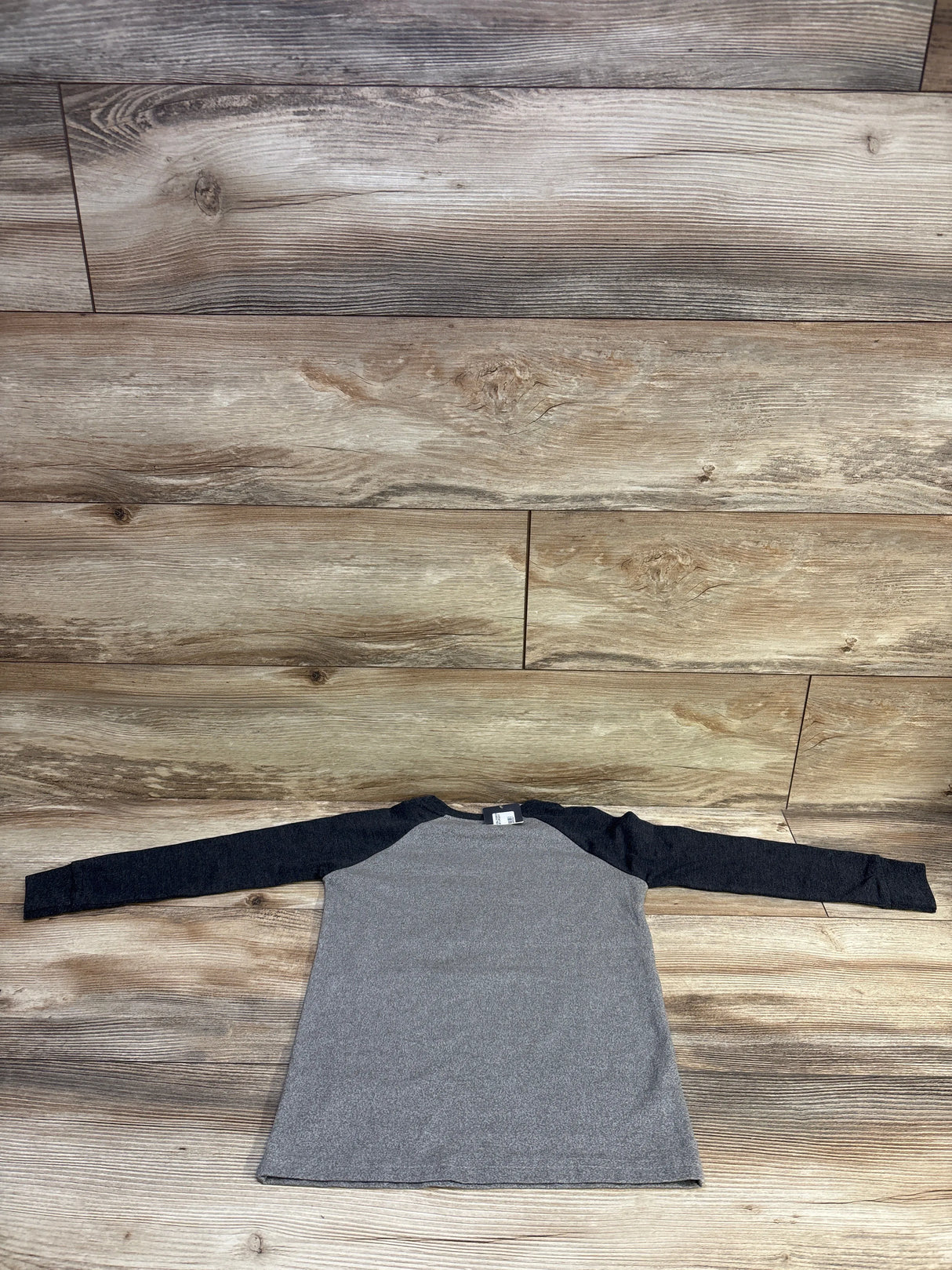 Flat-lay of toddler long-sleeve shirt showing heather gray body and dark raglan sleeves, size 4T, on wood background