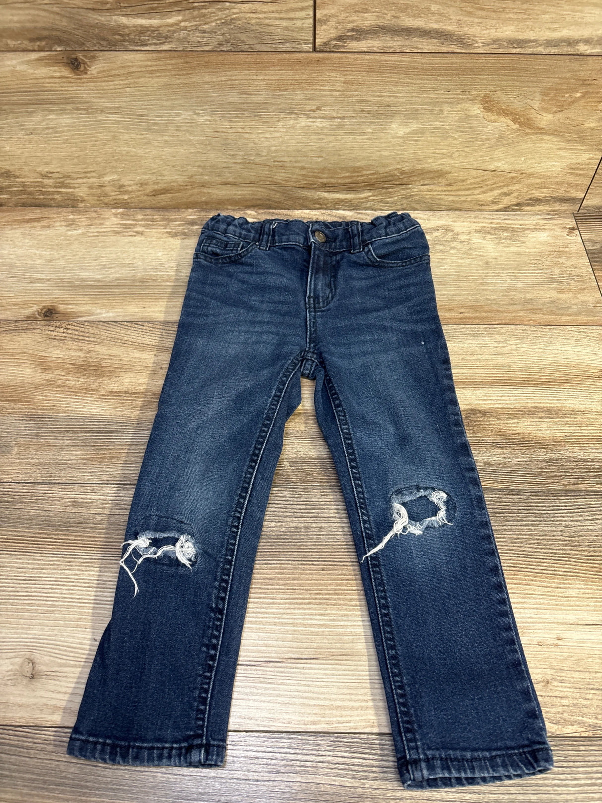 Front view of Okie Dokie toddler blue distressed jeans (4T) showing ripped knees and elastic waist on wood floor