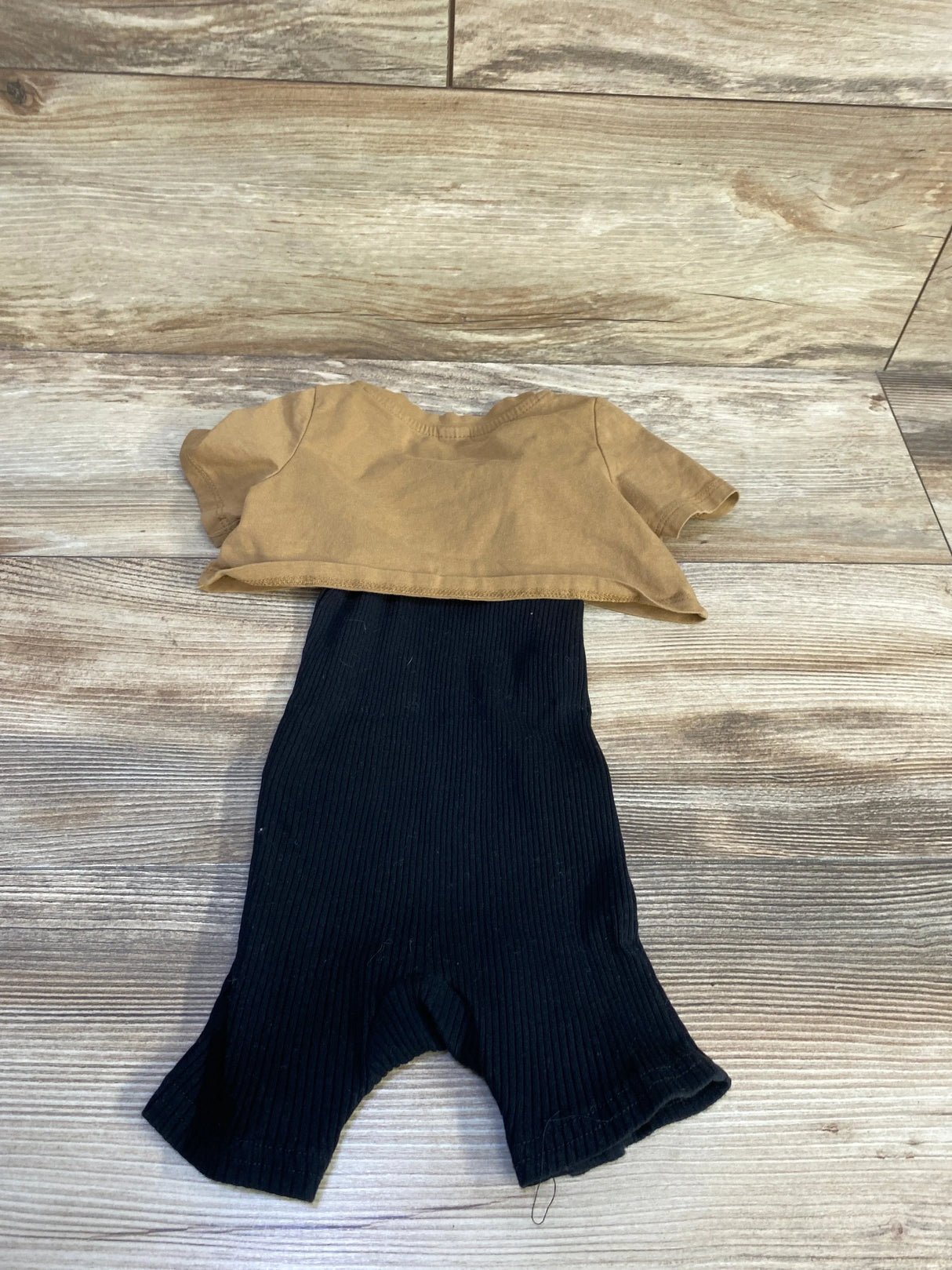 Flat lay of 2-piece baby set: brown cropped tee and black ribbed romper, size 12–18 months, on wood floor