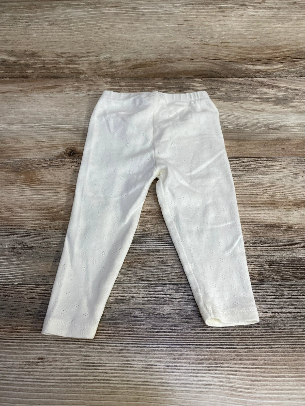 Flat-lay white Viverano organic pointelle baby leggings (3-6m) showing eyelet knit and elastic waist on wood background