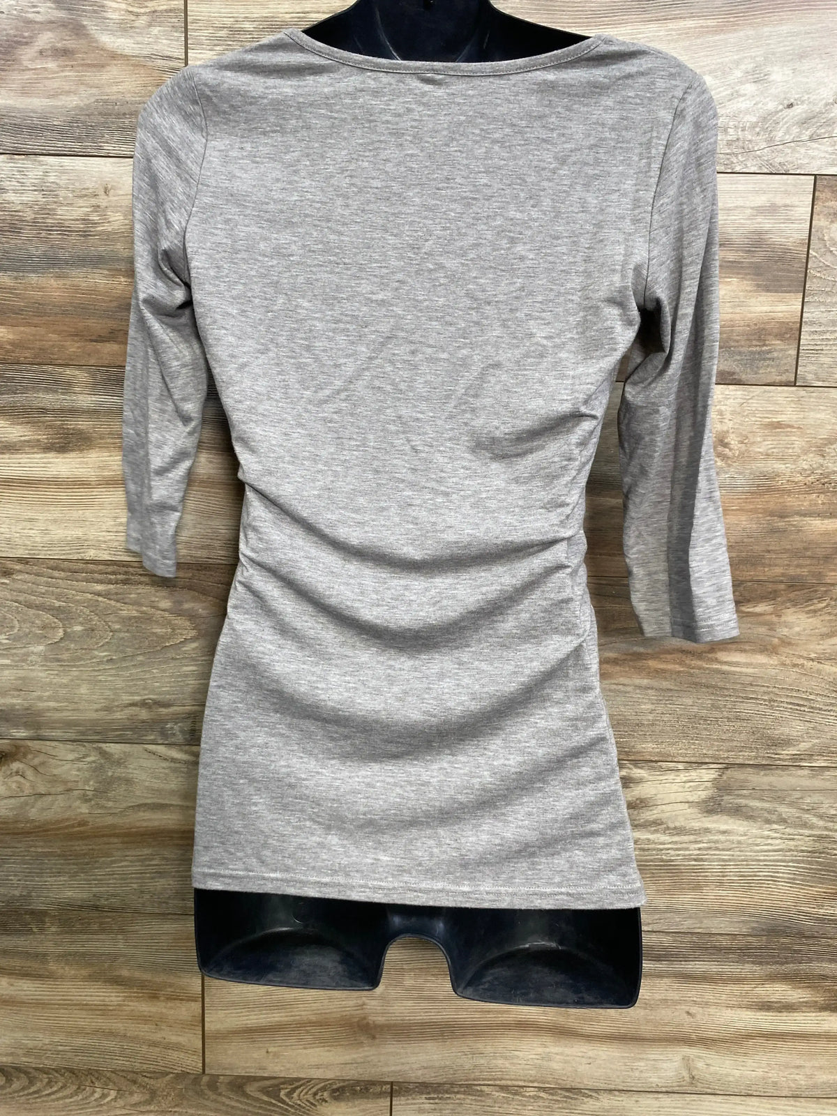 Front view of gray 3/4 sleeve ruched shirt in size Small showcasing gathered side ruching on a black mannequin against a wood background