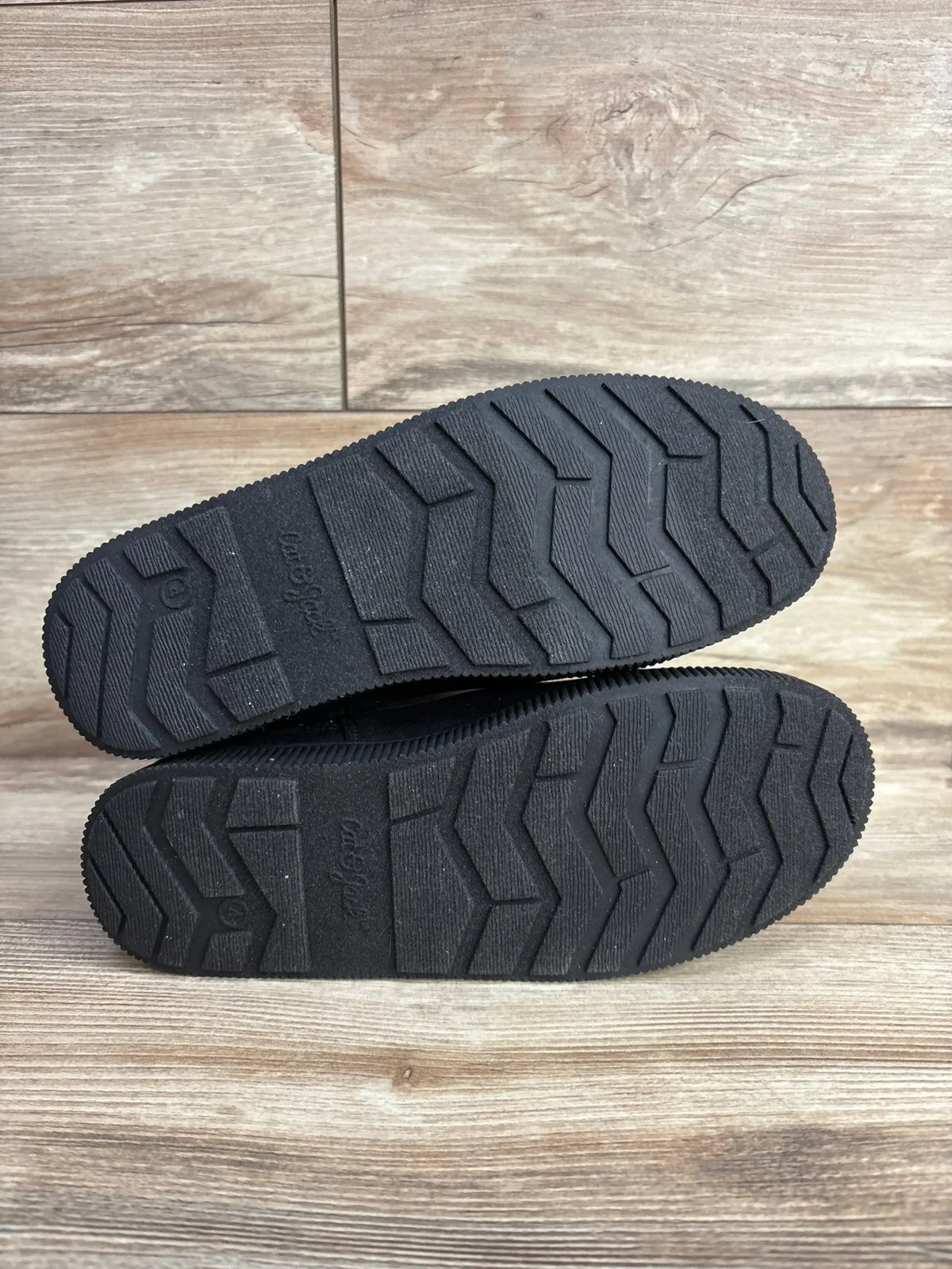 Bottom view of Cat & Jack Holland shearling-style kids boots showing black rubber zigzag tread on wood floor