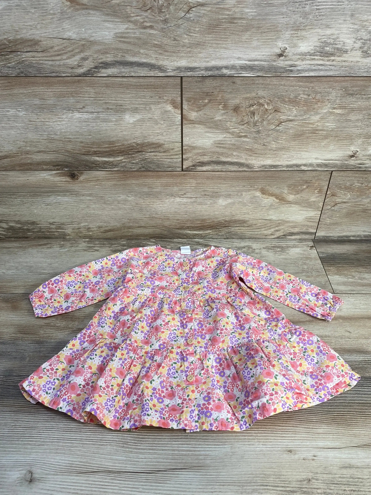 Front view of H and M floral button front tiered long sleeve dress pink size 9m on wood plank floor