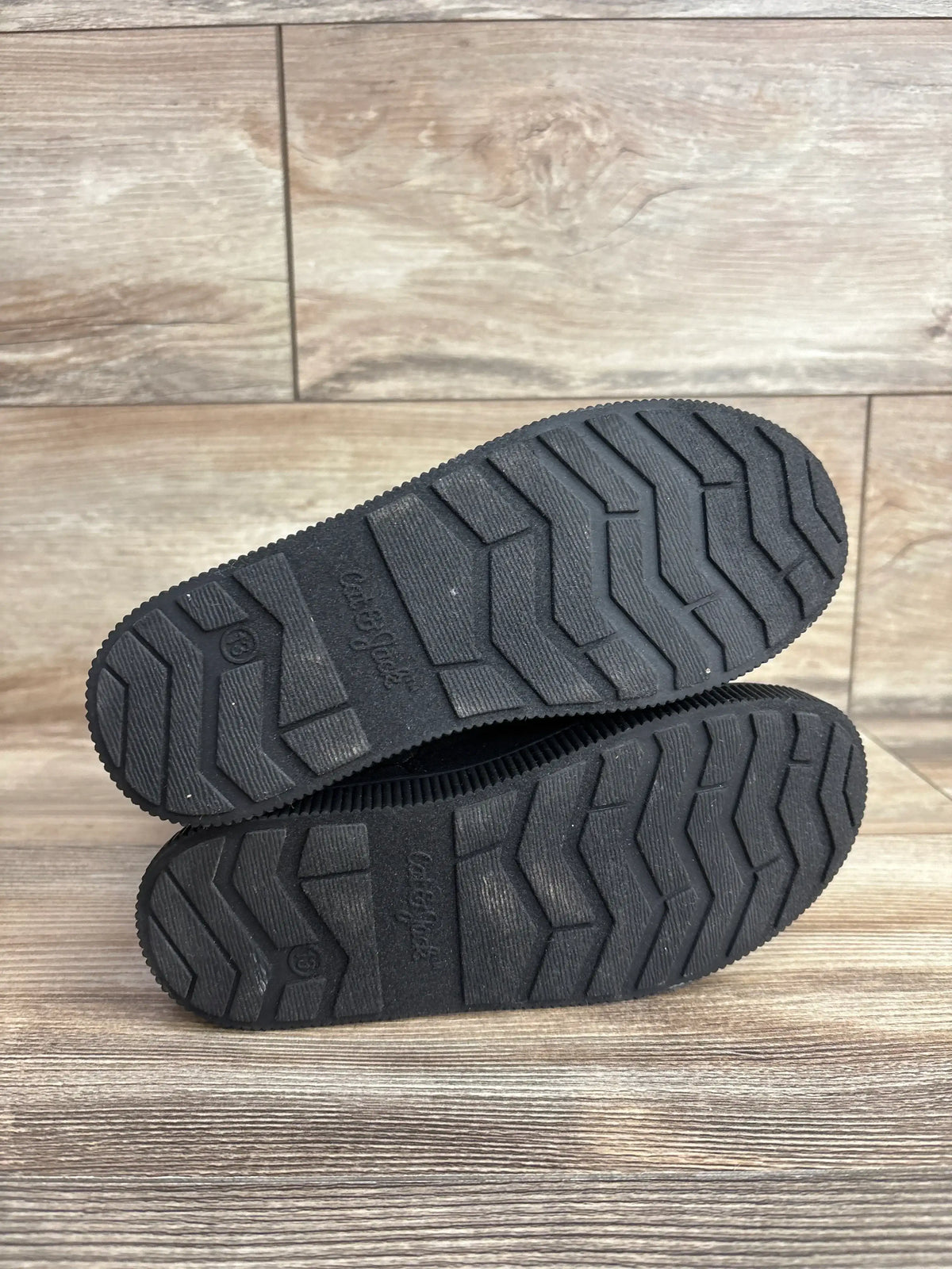 Bottom view of Cat & Jack Natalia tall shearling boots size 13C showcasing black rubber zigzag tread on wood floor