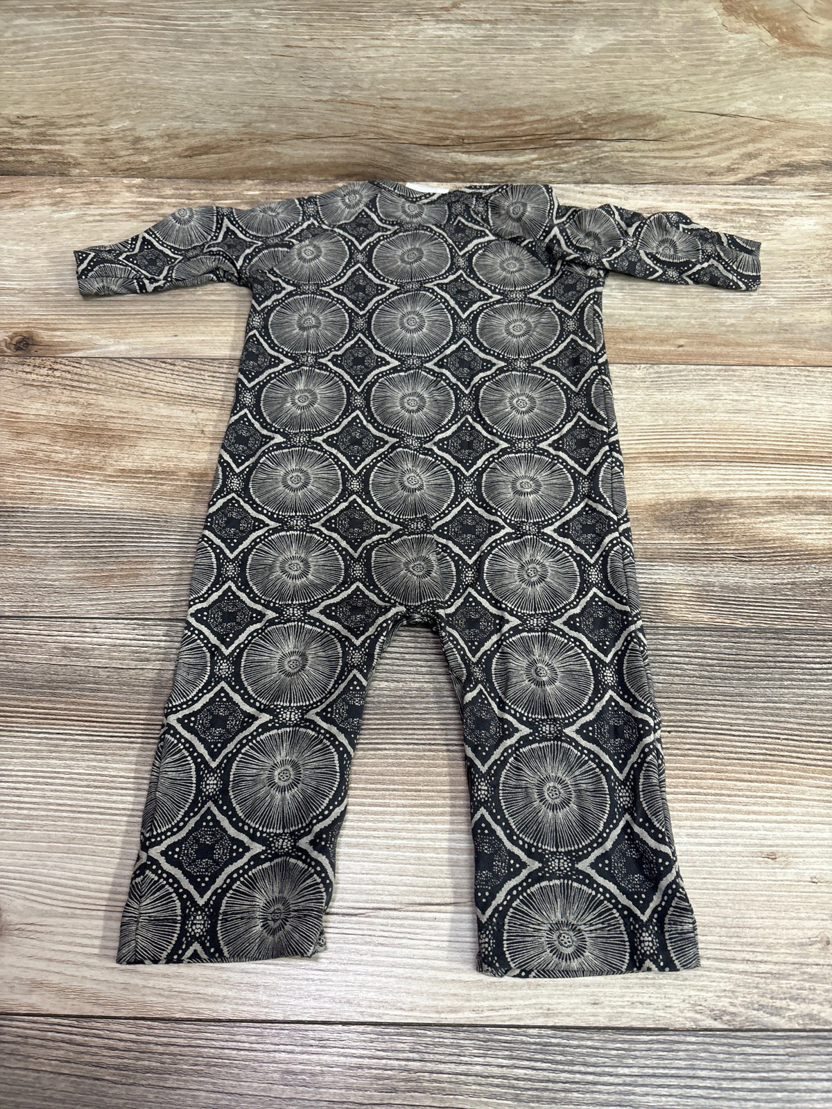 Flat lay of The Woods by Kate Quinn Beechwood Modal Coverall showcasing grey circular geometric pattern on wood background