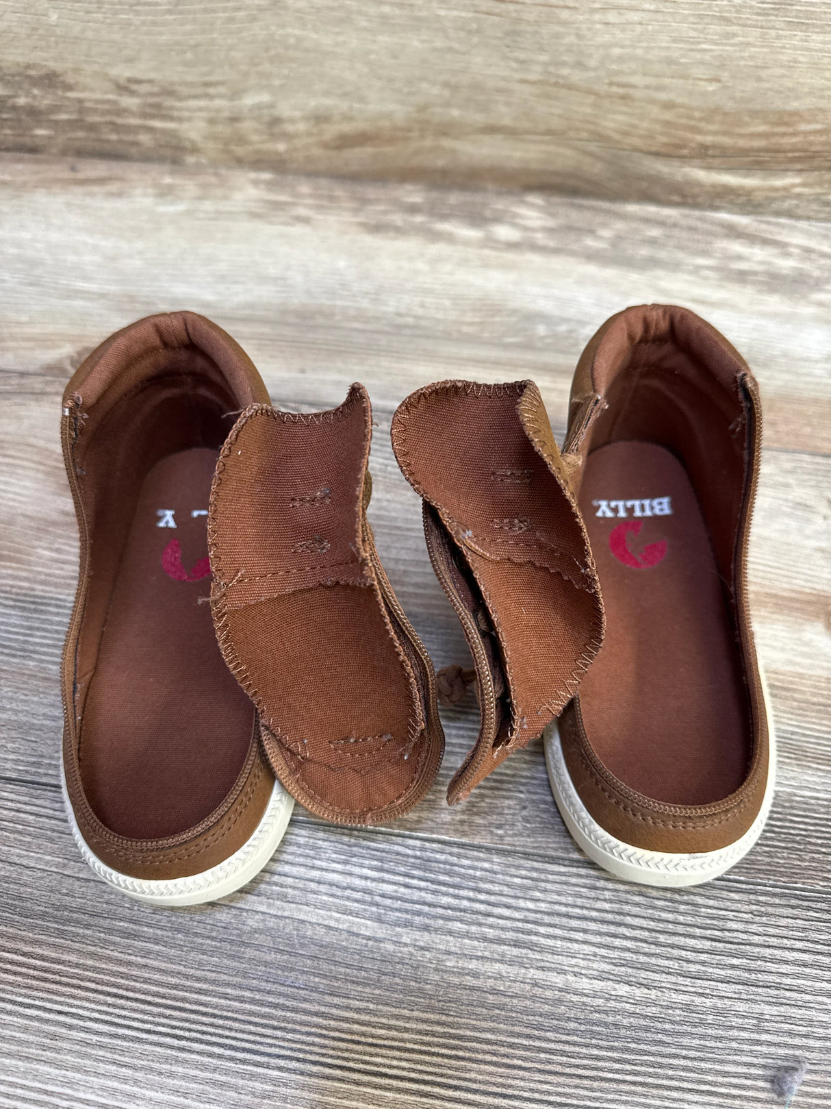 Top-down view of Billy Footwear Harmon high-top toddler sneakers showing tongues pulled out and BILLY insole on wood floor