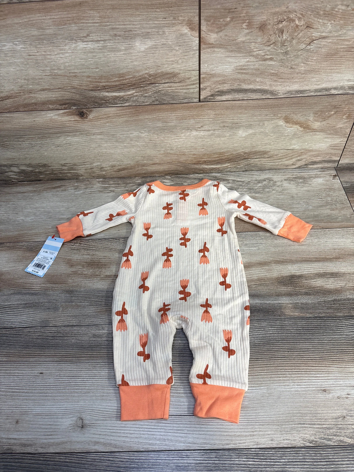 Infant ribbed long-sleeve romper with orange floral pattern and orange cuffs, size 0-3M, on wood floor
