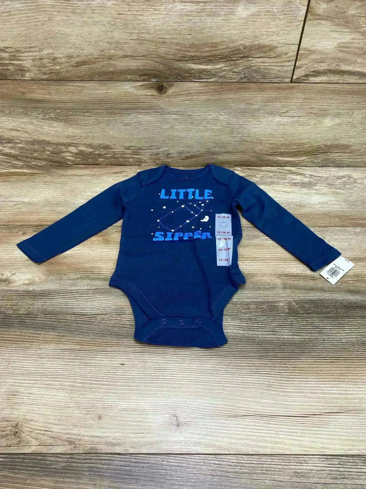 Flat lay of Old Navy blue long-sleeve bodysuit showing Little Sipper graphic, snap crotch, 12-18 months on wood background