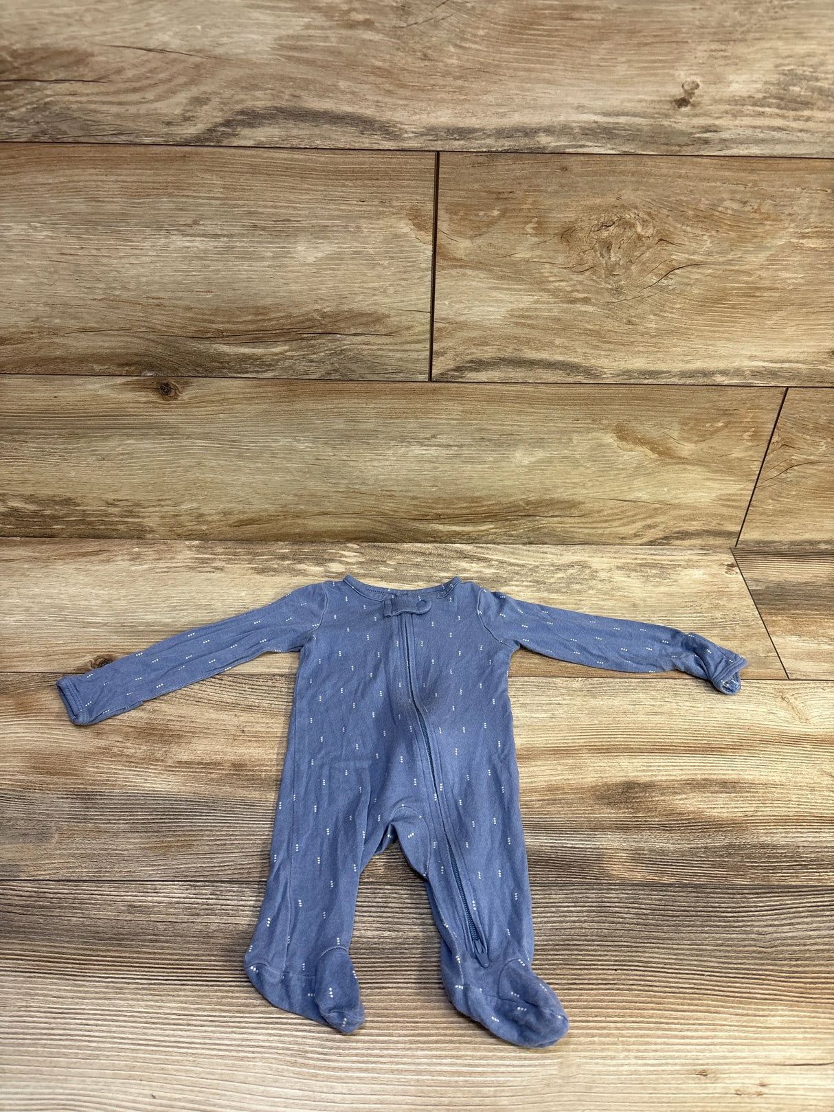 Top-down view of Just One You PurelySoft newborn blue footed sleeper showing front zipper and small white dash print on wood background