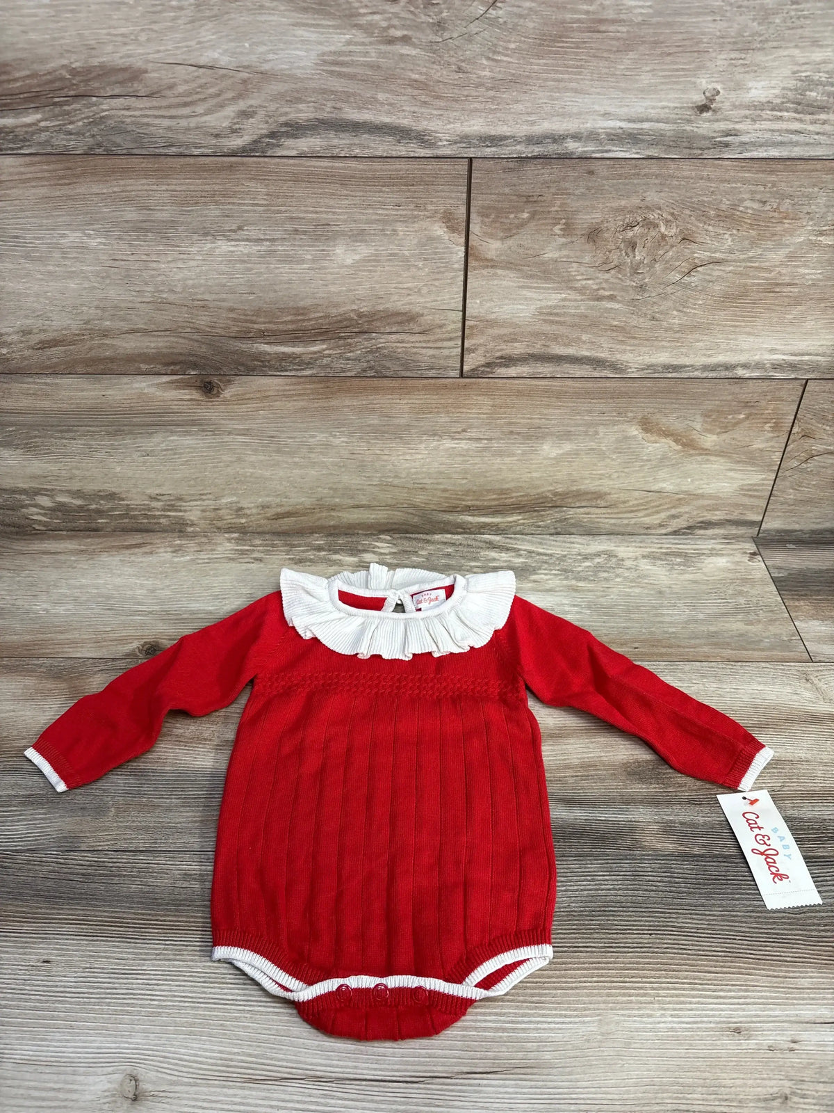 Red long sleeve baby bodysuit with white ruffled collar on wood background, Cat & Jack tag