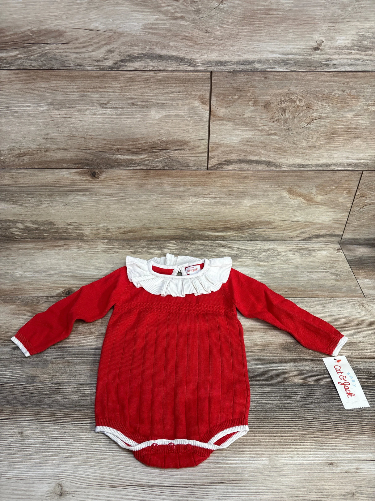Red long sleeve baby bodysuit with white ruffled collar on wood background, Cat & Jack tag