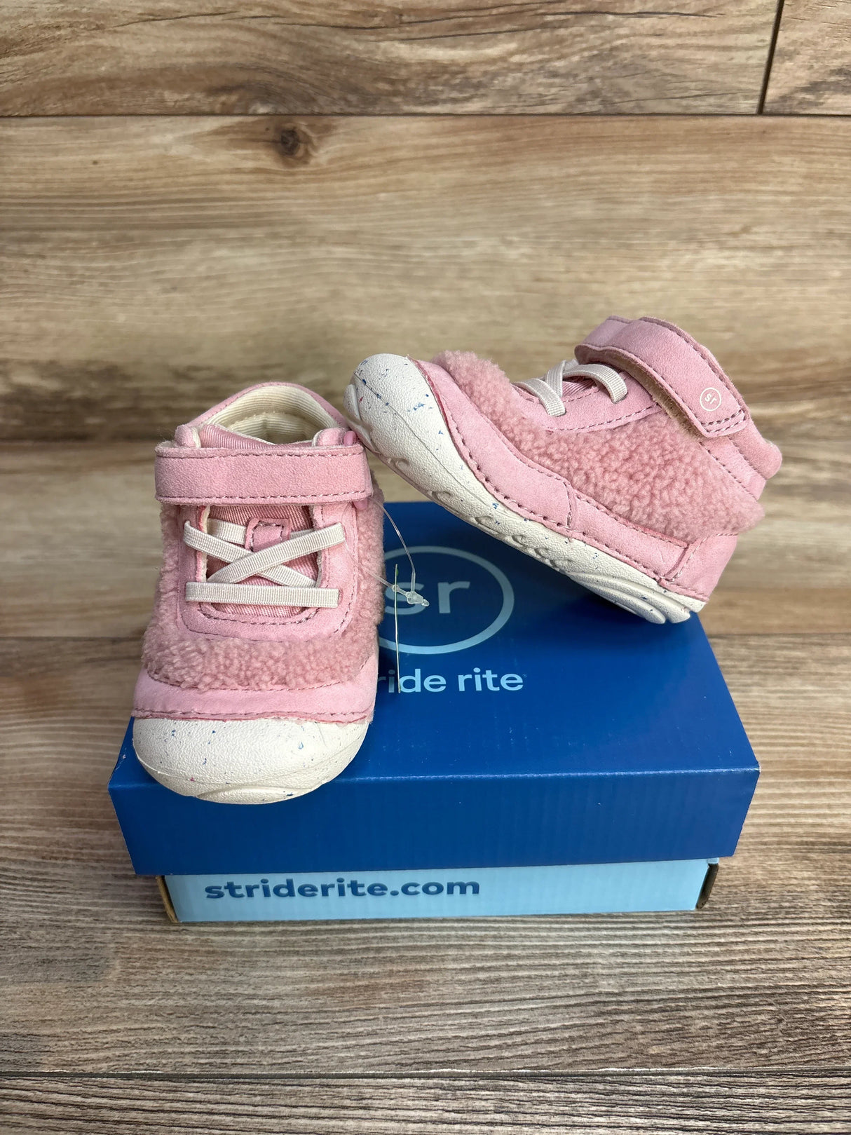 Pink toddler shoes with velcro straps on a blue Stride Rite shoebox on wooden background