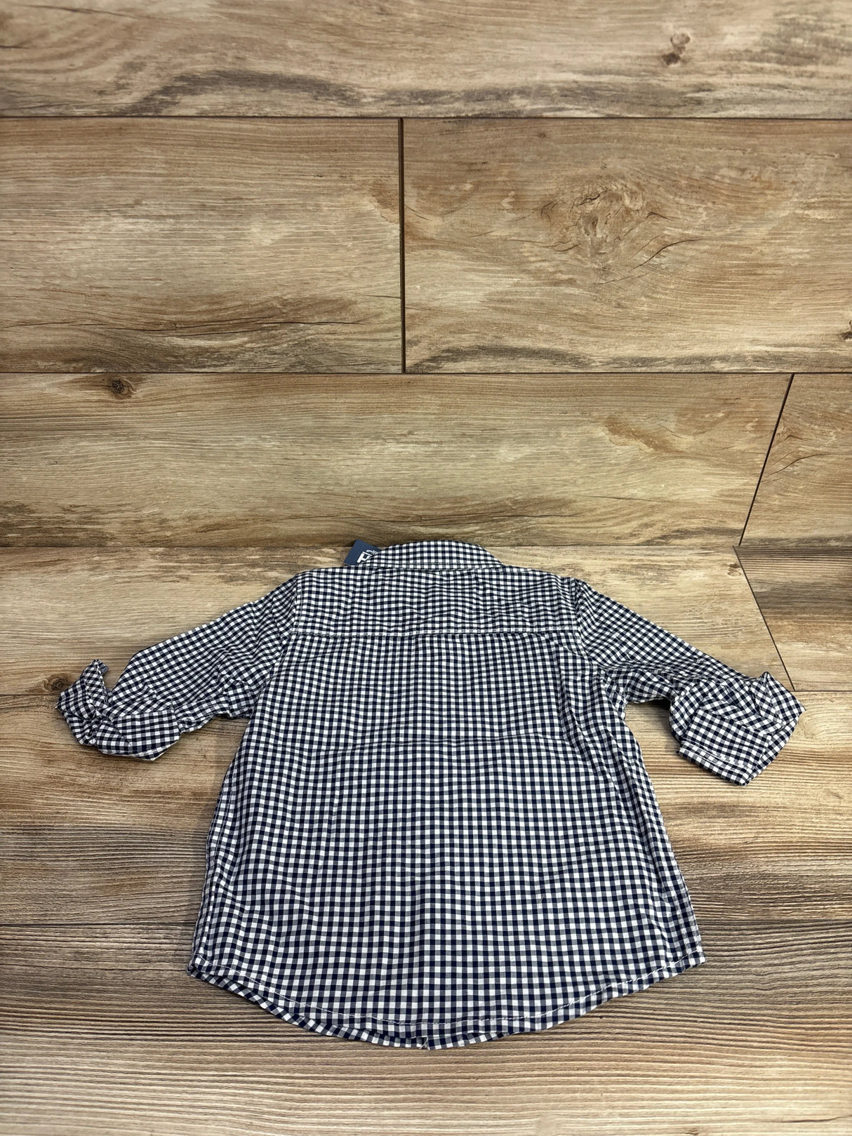 Back view of long sleeve navy and white gingham checkered toddler shirt on wood floor