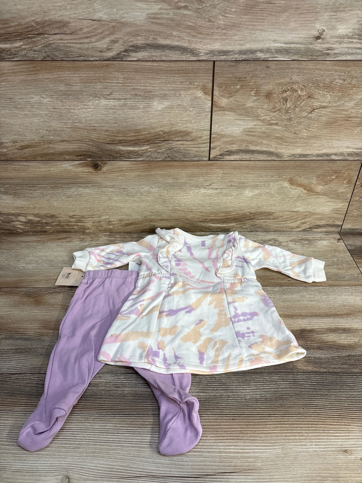 Baby outfit with pastel tie-dye dress and lavender leggings on wood background