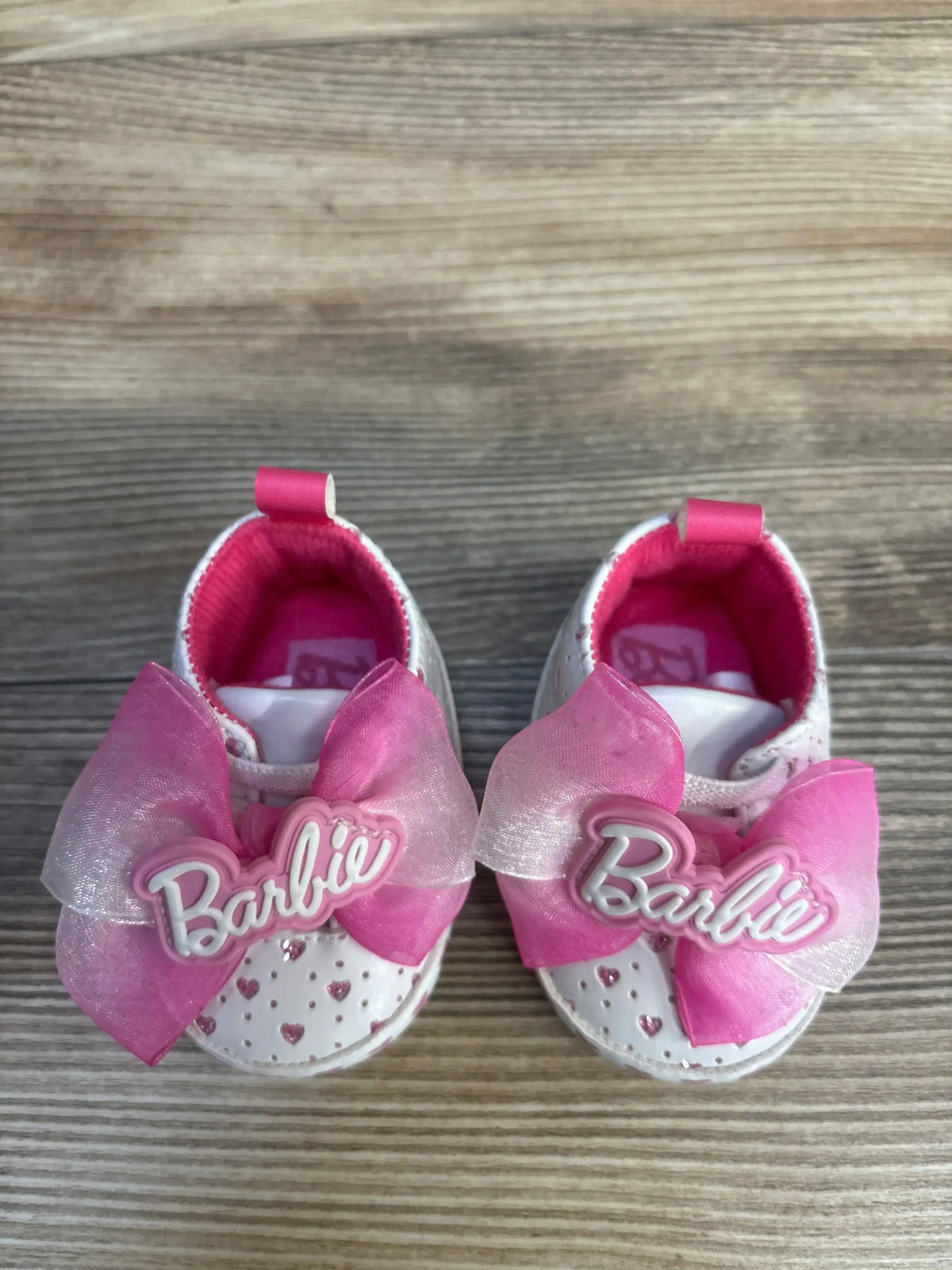 Front view of Barbie Soft Sole sneakers size 1C showing white sole, pink heart appliques and ribbon bows on white