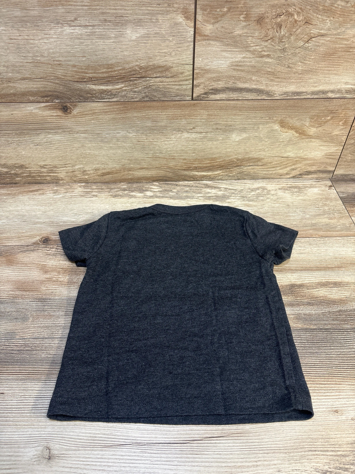 Kids charcoal gray short sleeve t-shirt laid flat on wood background
