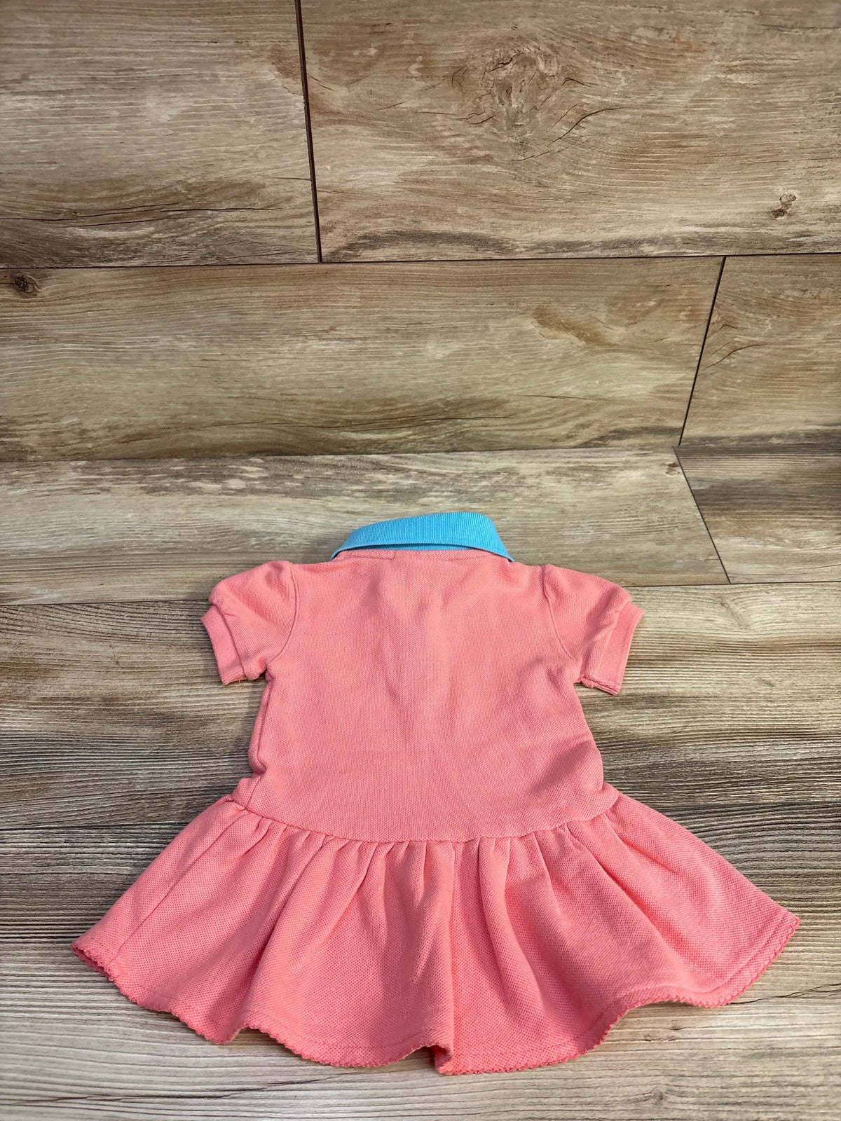 Back view of NHL Vegas Golden Knights coral polo dress, size 3/6 months, with short sleeves and flared skirt on wood flooring