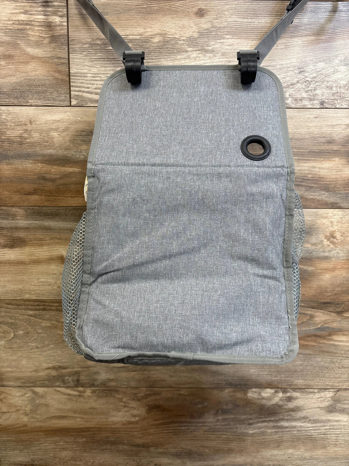 Overhead view of Maliton hanging diaper caddy organizer in grey showing closed front flap, hanging straps with clips, and mesh side pockets on wood floor