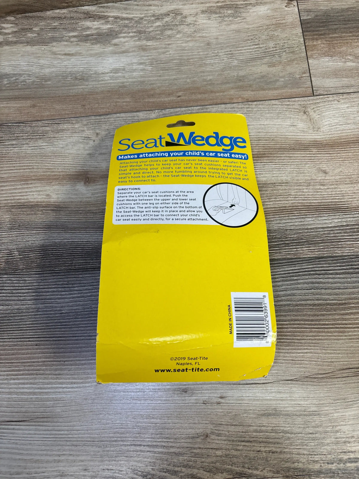 Top-down view of SeatWedge packaging showcasing the large SeatWedge headline and usage directions on a wood floor background