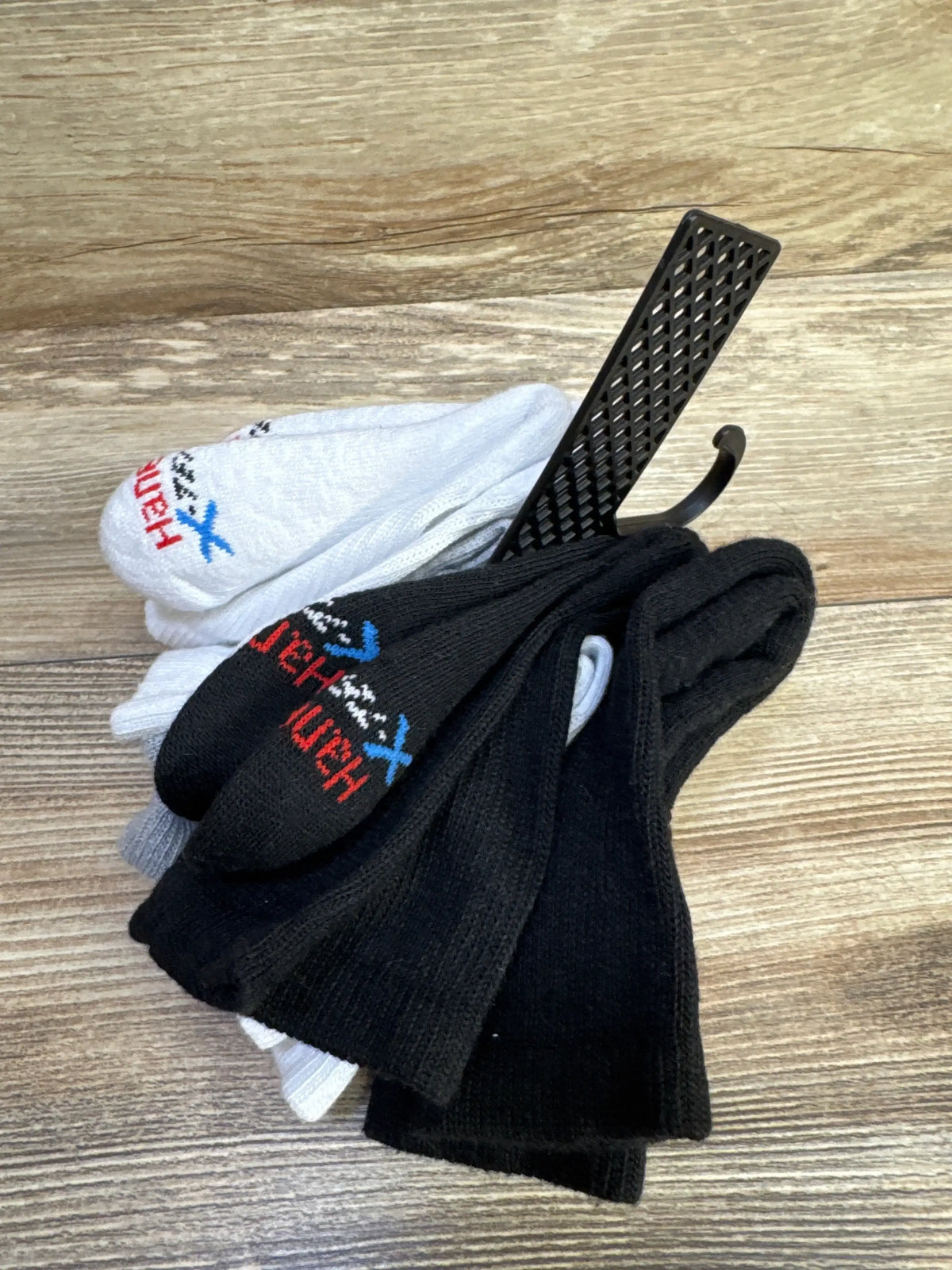 Top view of new Hanes five pack of black and white socks in size M on a wood grain surface