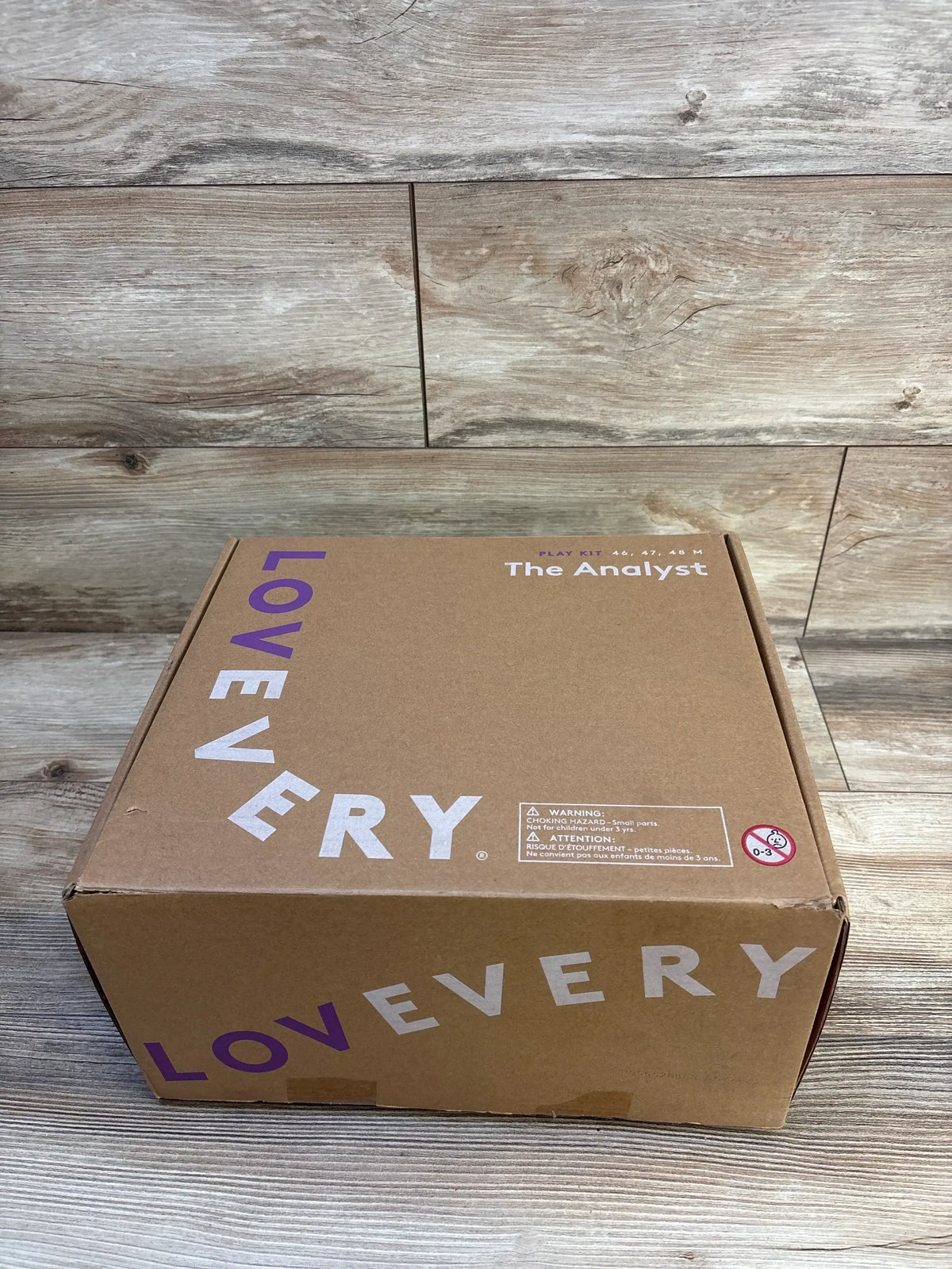 Lovevery play kit box for kids, labeled The Analyst, on wood floor background