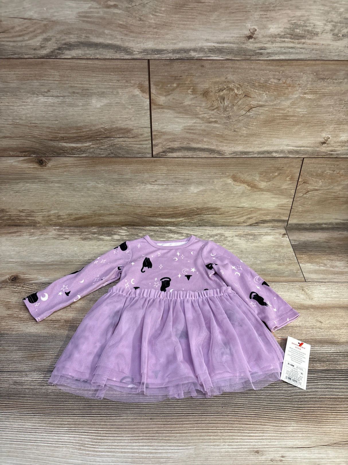 Top-down view of Cat & Jack baby long-sleeve purple Halloween dress showcasing black cat, moon and star print and layered tulle skirt on wood background