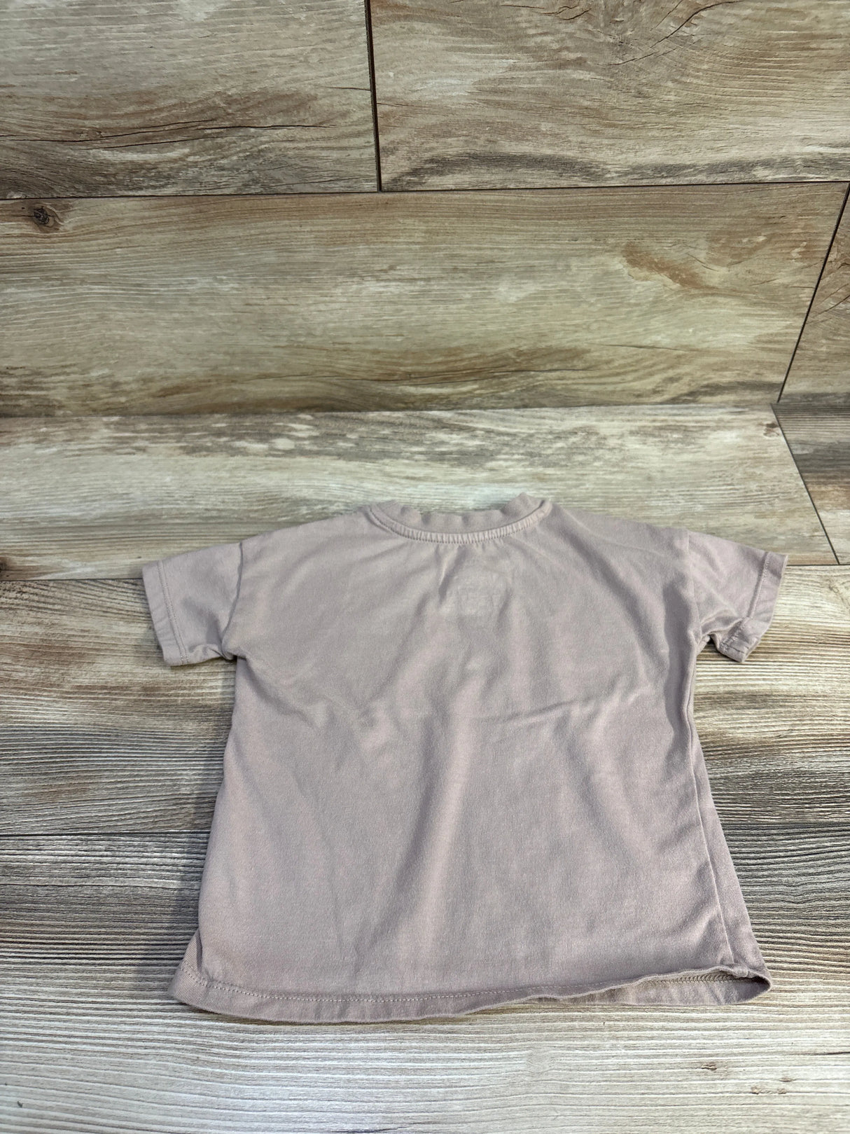 Flat lay of Grayson mini shirt (brown, 2T) showing back view with short sleeves, crew neck, and curved hem on wood background