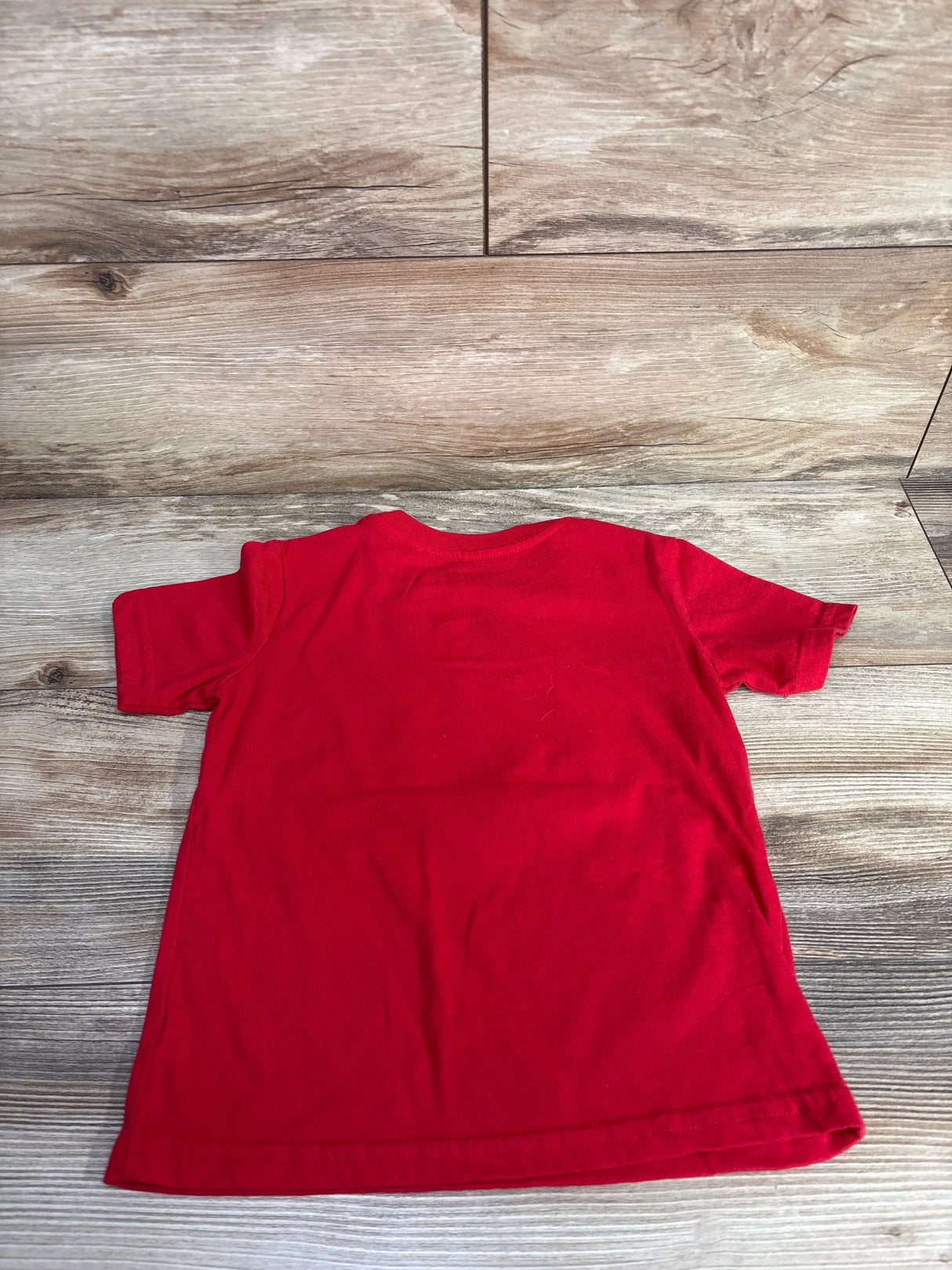 Back view of red Disney Stitch 4th of July toddler T-shirt size 5T showing plain back on wood plank background