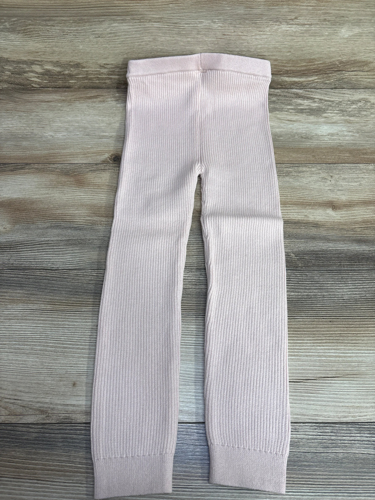 Flat lay of Baby Gap pull-on ribbed light pink leggings size 5T showing elastic waistband and cuffed ankles on wood background