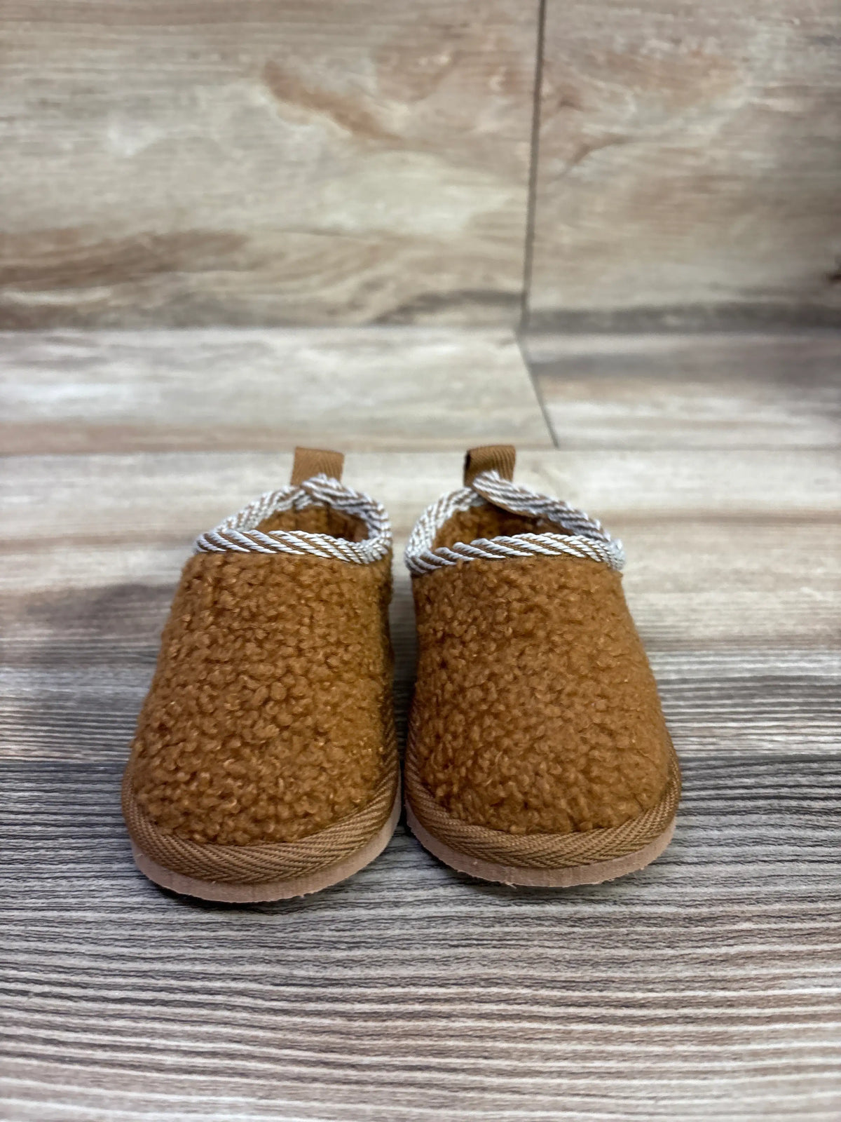 Front view of brown Bearpaw Tabitha slippers with sherpa uppers and rope trim on a wood-patterned background