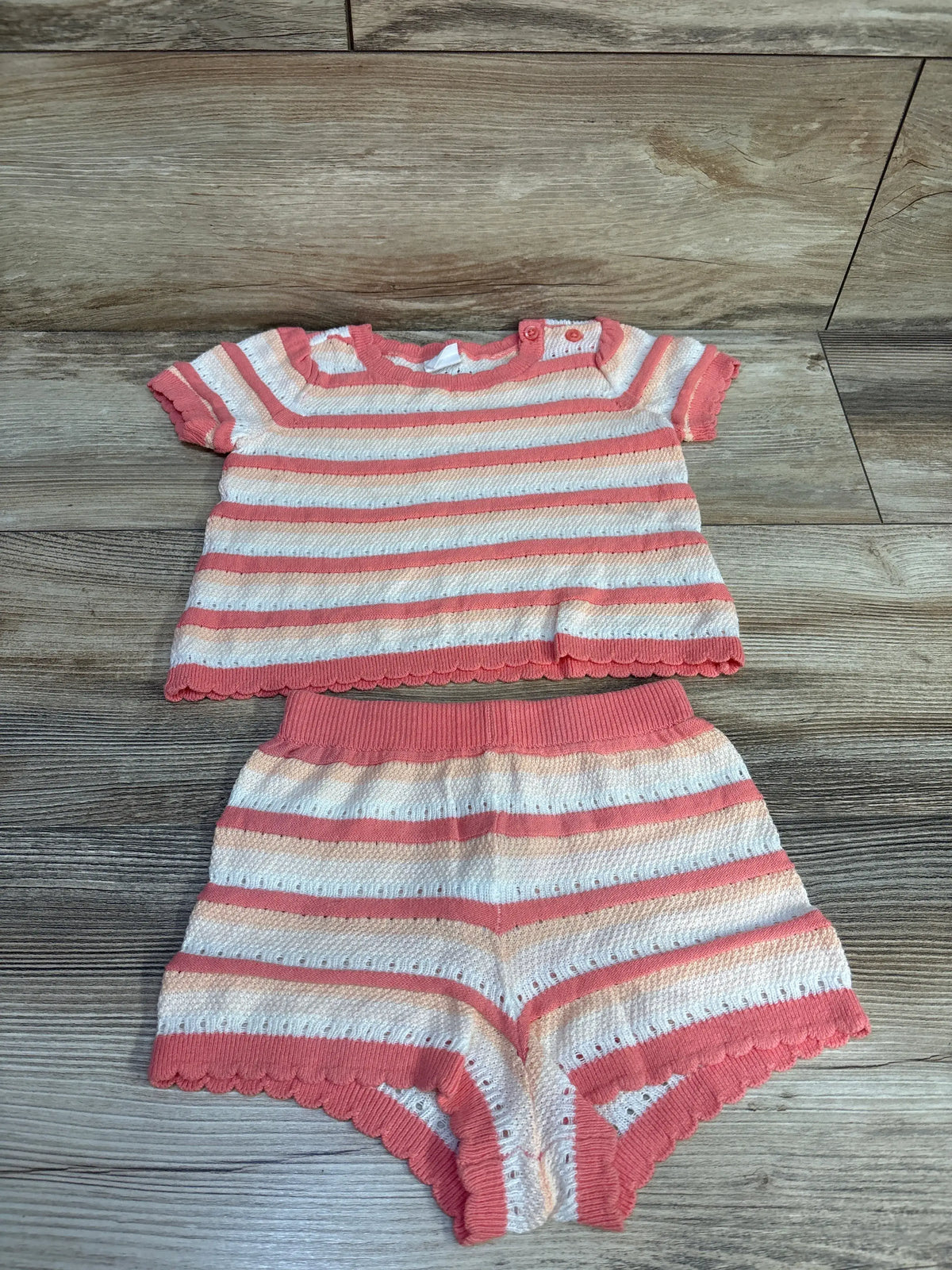 Top view of Baby Gap 2pc striped crochet shirt and shorts set showcasing pink and white stripes on a wood floor