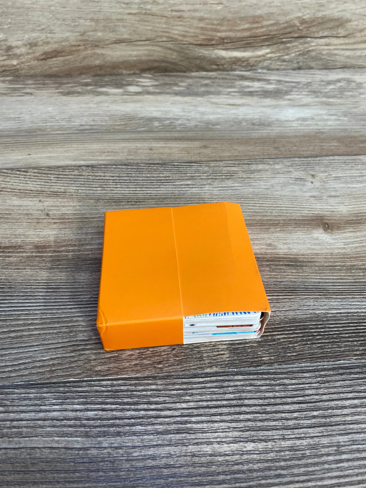 Stack of colorful cards partially enclosed in an orange sleeve on a wooden surface