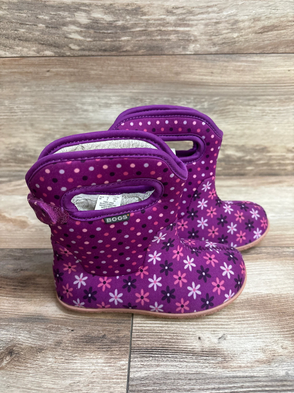 Purple Bogs toddler boots with polka dot and floral print on wooden floor