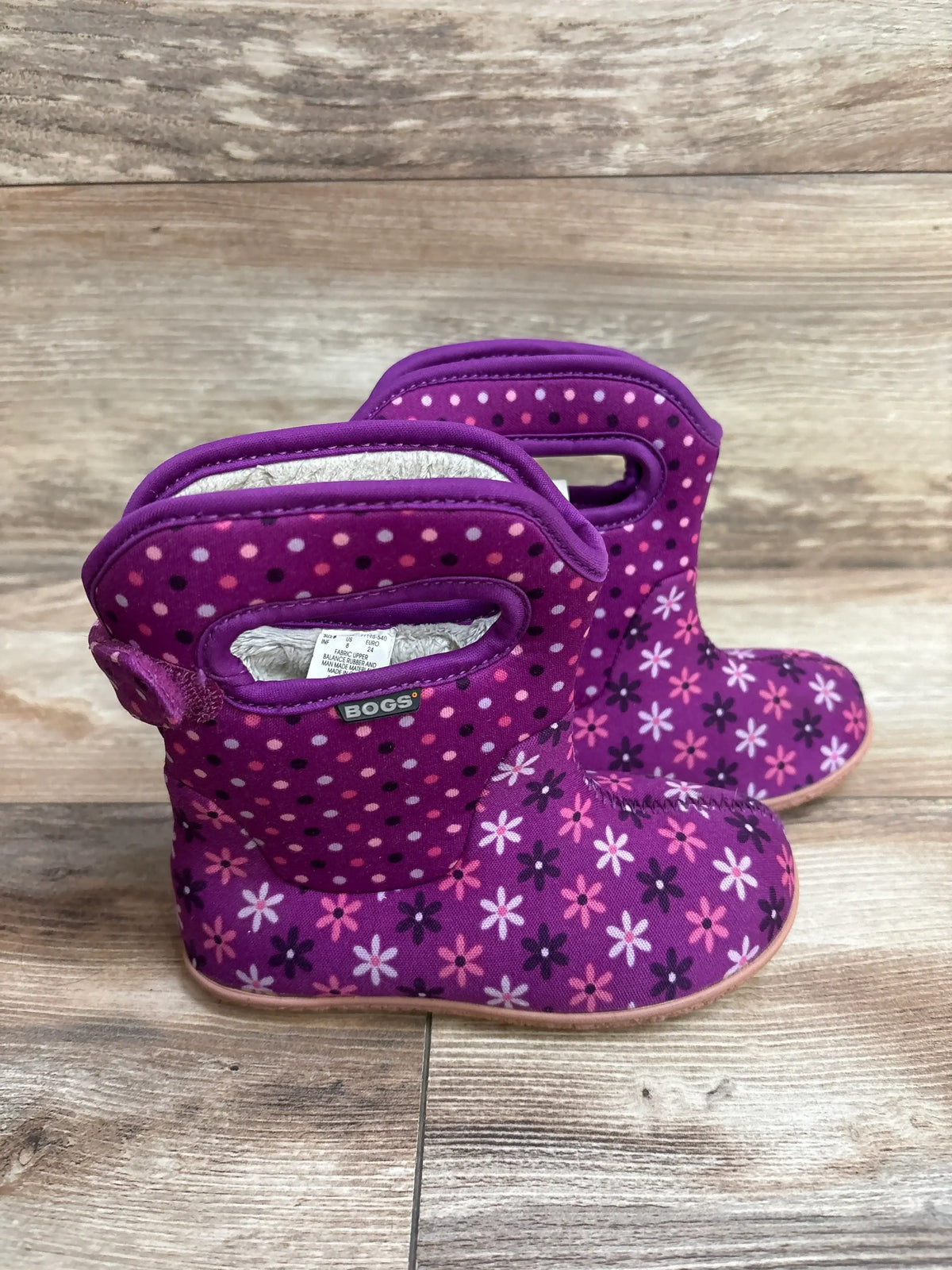 Purple Bogs toddler boots with polka dot and floral print on wooden floor