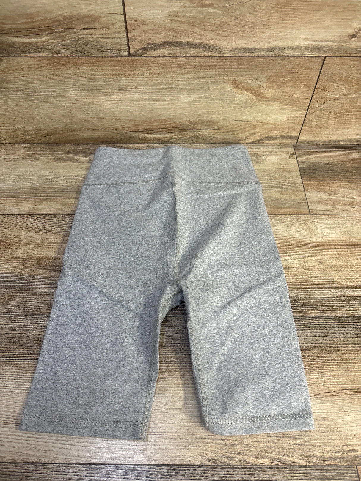 Front view of gray Gap maternity bike shorts showcasing a smooth wide waistband with flat seams on a wood floor