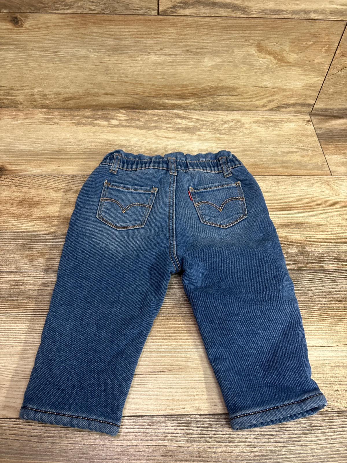 Back view of Levi’s High Loose Lined Jeans in blue showcasing back pockets and elastic waistband on a wood grain surface