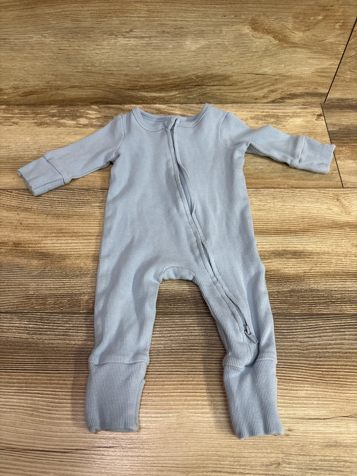 Light blue Cotton On Baby organic ribbed sleeper for infants 0-3 months on a wooden background
