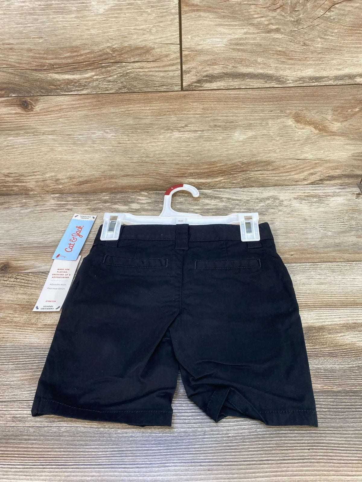 Back view of Cat & Jack black toddler school uniform shorts showing back welt pockets and belt loops on wooden floor background