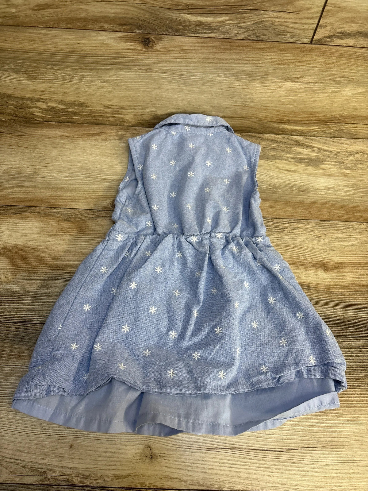 Flat lay of Draper James chambray sleeveless dress (3T) showing white star embroidery and gathered waist on wood floor