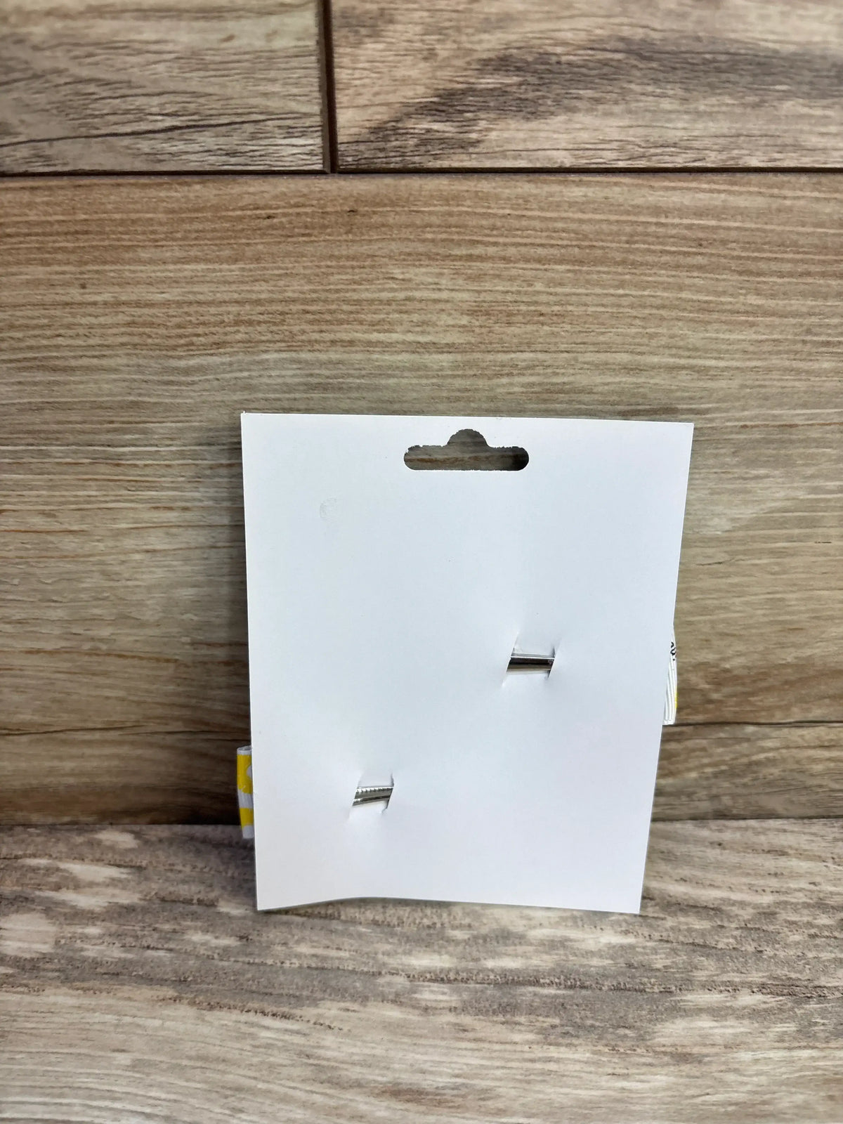 Back view of 2 pack fanned-out baby hair bows showing white backing card, two silver clips and yellow banana bows peeking from sides on wood surface