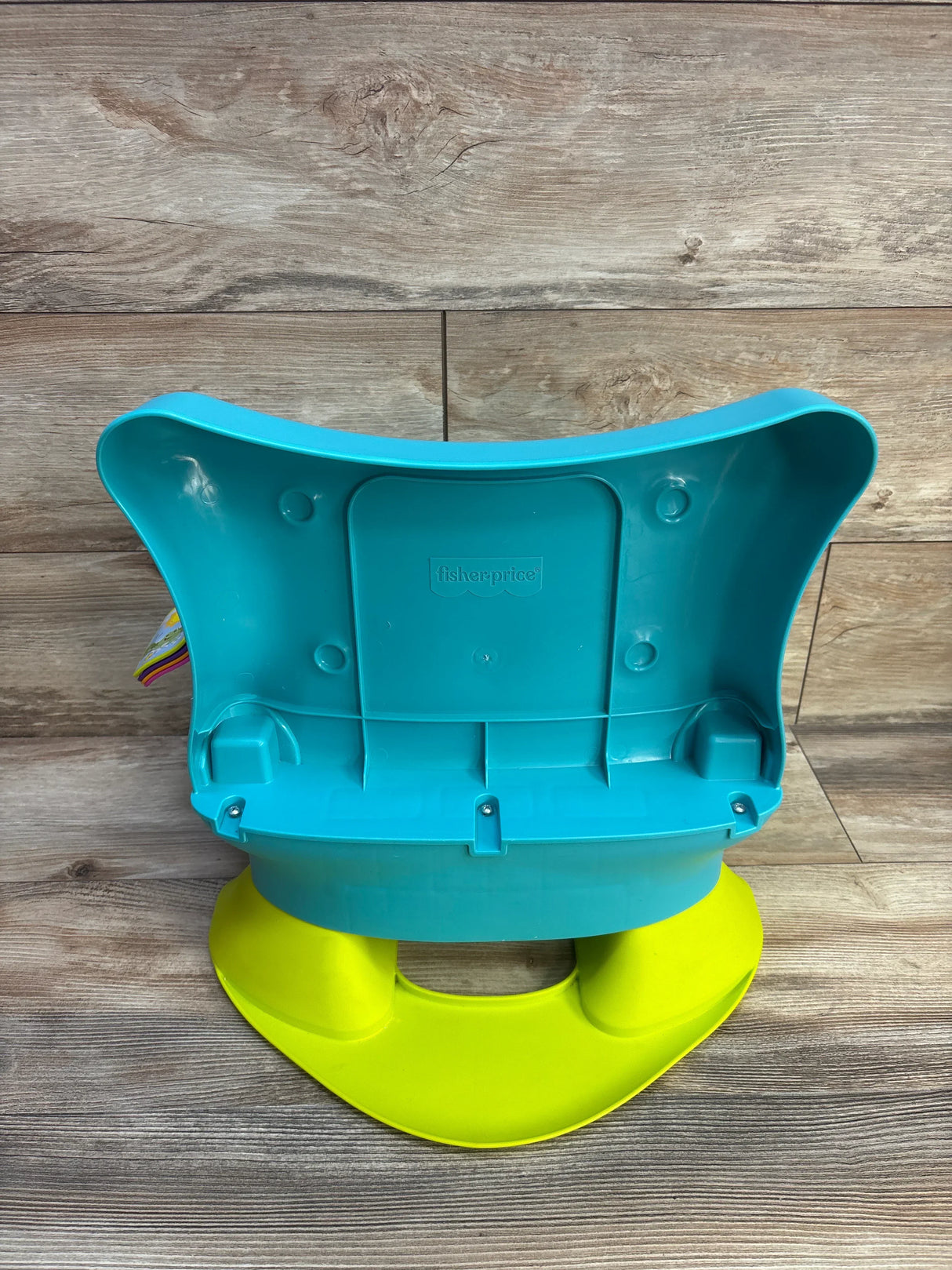 Back view of Fisher-Price Smart Stages chair in teal showing plastic seat back and yellow rocker base on wood floor