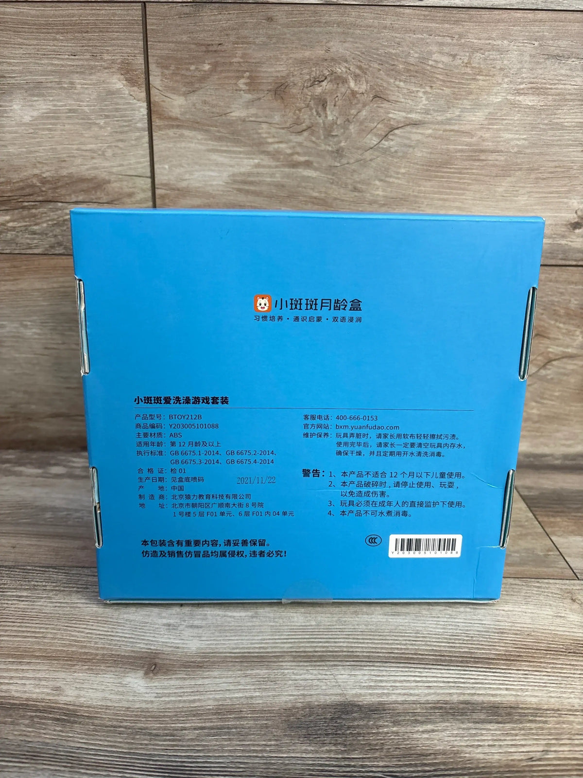 Back view of Banban Bath Play Set box showing Chinese branding, product information, and barcode on a wooden floor background