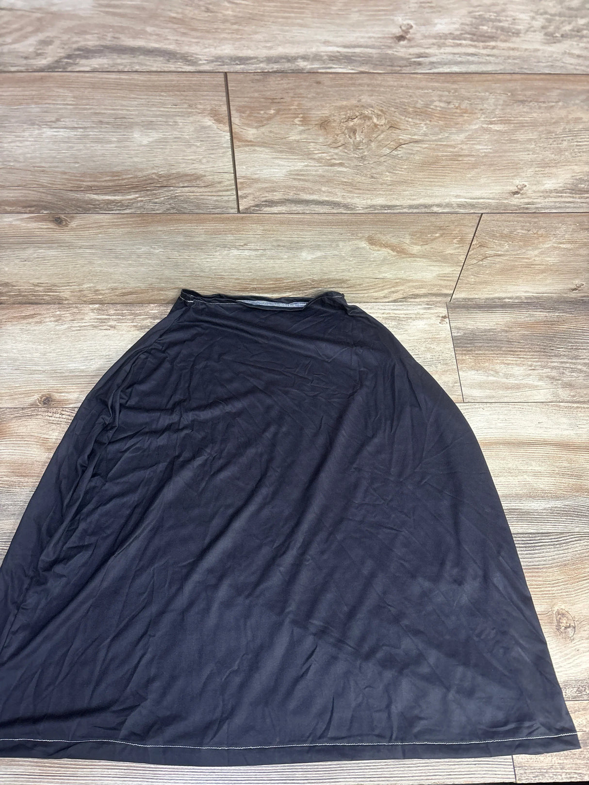 Flat lay of black car seat and nursing cover showing poncho-style shape and elastic neckline on wood floor