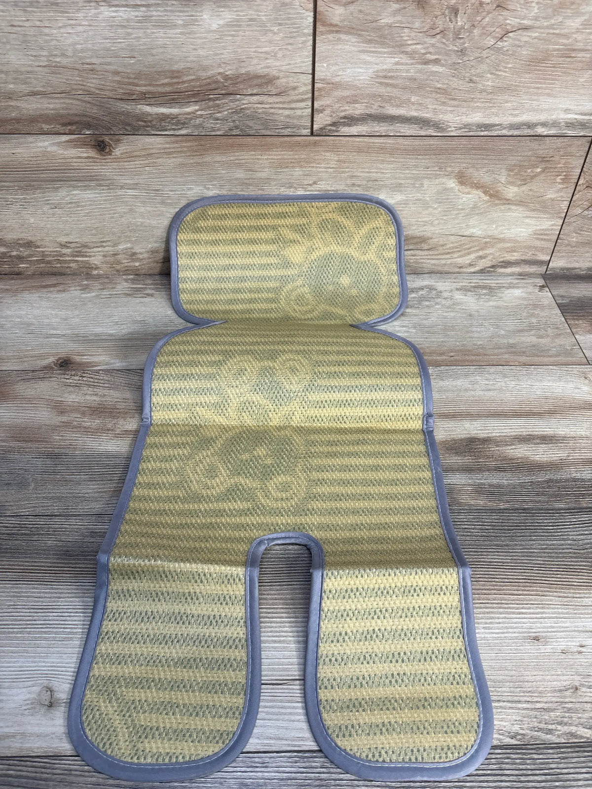 Top view of Universal Stroller Cool Seat Liner, breathable mesh cooling surface with head and leg cutouts on wood background